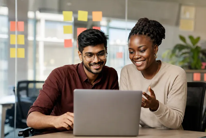 Two developers reviewing code together on a laptop