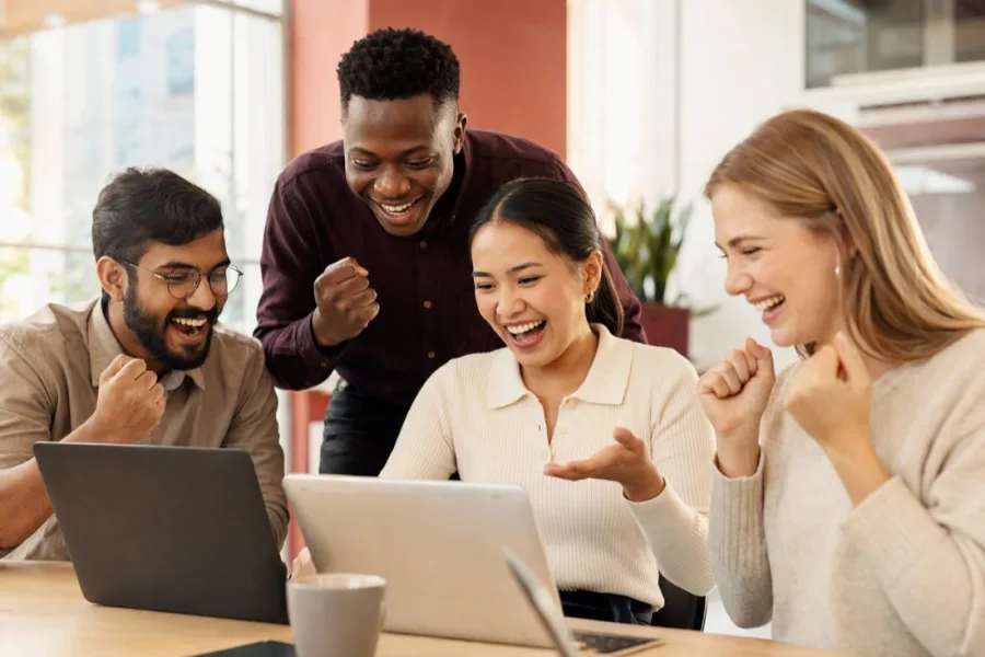 Four young professionals working together over charts on laptops