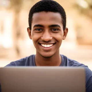 A smiling young man student holding a laptop outdoors